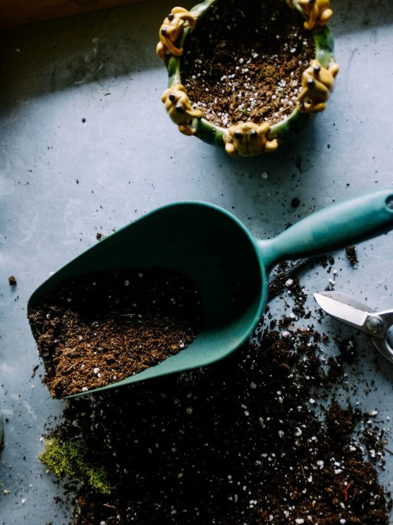 green metal garden shovel filled with brown soil